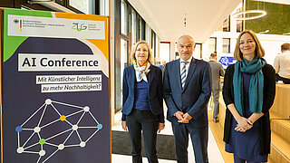 Frau Lottermoser, Stefan Demuth und Constanze Haug neben einem Roll-up der AI Conference